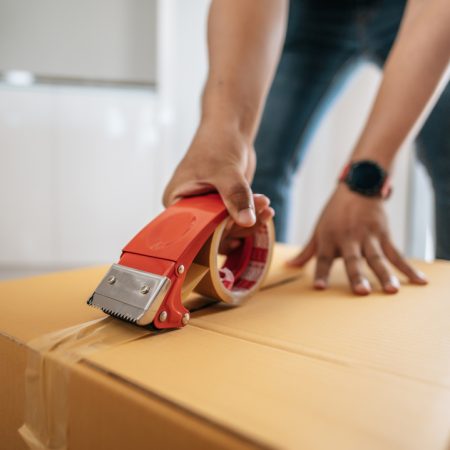 Close up hand of man use glue tape to close cardboard box, sealing big box for packing moving, new house concept, Selective focus	cardboard box,